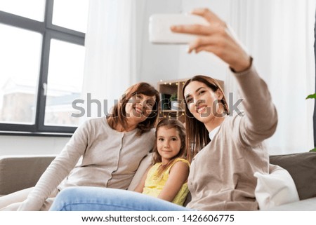 family, generation and technology concept - happy mother, daughter and grandmother taking selfie by smartphone at home