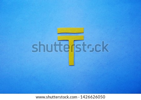 Kazakhstan currency symbol of tenge from paper on blue cardboard background