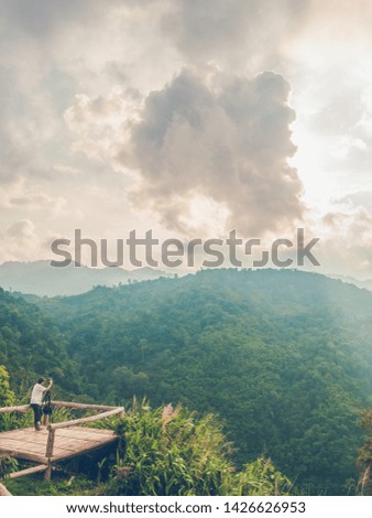travel in tropical forest and camping, adventure vacations concept from man photographer is taking picture of sunset mountains landscape with happiness and freshness.