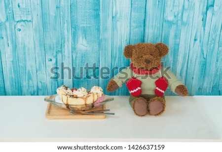 Teddy bear sit on blue background with ice creams.