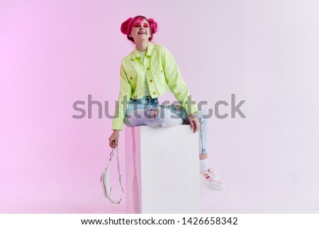 woman with pink hair with bag sits on the cube