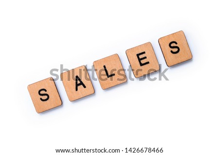 The word SALES, spelt with wooden letter tiles over a white background.