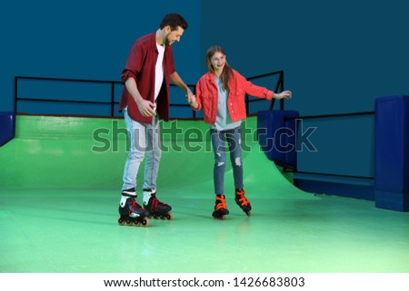 Father teaching her daughter roller skating at rink