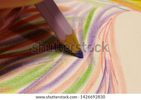 A simple stylus pencil macro photo lies on a green sheet of paper, pencils of different colors draw lines and pictures of a macro shot