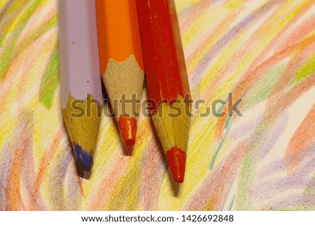 A simple stylus pencil macro photo lies on a green sheet of paper, pencils of different colors draw lines and pictures of a macro shot