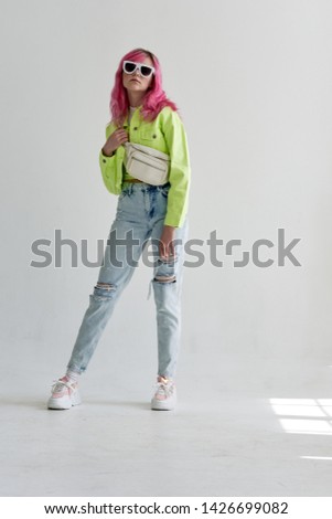 woman with pink hair in glasses in full growth in stylish clothes