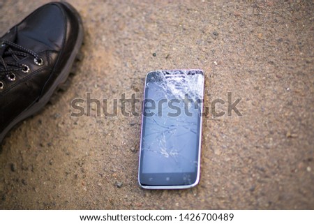 Person Picking Broken Smart Phone Cracked Screen on Ground