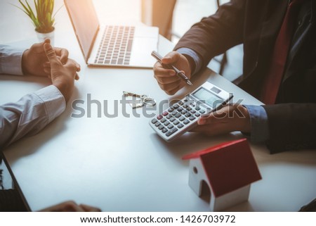 Real estate agent calculate Insurance fee for house and show to young couple. Business successful contract concept. Royalty-Free Stock Photo #1426703972