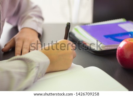 a high school student or a student writes in a notebook at a Desk, doing homework