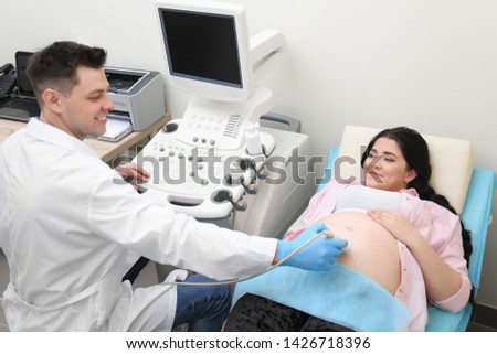Young pregnant woman undergoing ultrasound scan in clinic