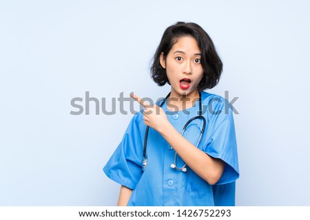 Surgeon doctor woman surprised and pointing side