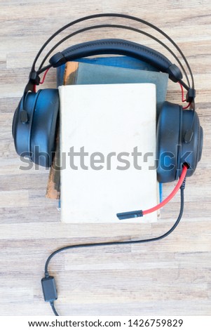 Audio book concept. Headphones and books on wooden table. Top view with copy space.