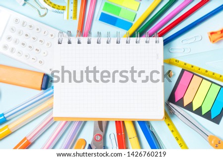 Back to school concept with school supplies on blue background, copy space on ruled paper notebook