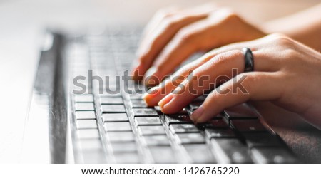 Woman working at home office hand on keyboard close up on wooden table background