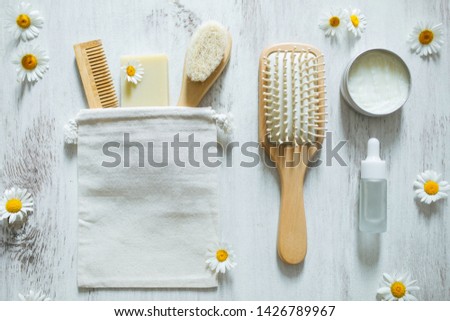 Natural eco and organic cosmetics products for hair care and facial treatment. Wooden hairbrush, essential oil, vegan soap, lotion and herbal mask with chamomile flowers. Top view on white background. Royalty-Free Stock Photo #1426789967