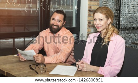 Business people, man and woman. Signing financial documents sitting at the table in the office.
