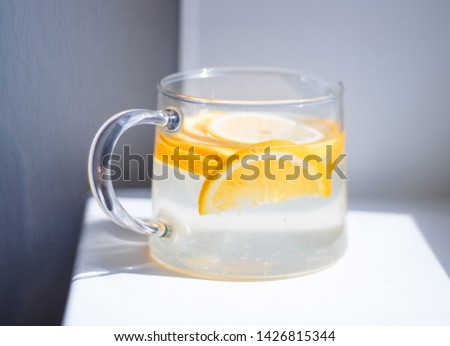 pitcher with lemonade and water sliced oranges and lemon on white table close-up with blurred background
