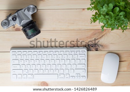 top view of the photographer workplace with a white keyboard and mouse on the wooden table