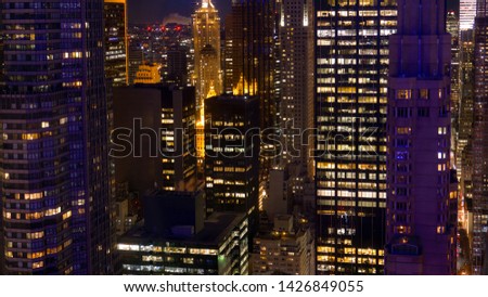 Spectacular high rise office buildings tower above the bustling streets of New York at night. Breathtaking shot of countless skyscrapers illuminated at night in the financial district of a modern city