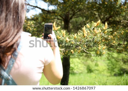 A young, cute girl with a smart phone photographs a beautiful nature.-Image
