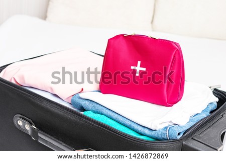 Road suitcase, clothes for the road and first aid kit for extraordinary event, top view, cropped image, toned