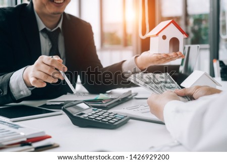 Real estate agents holding model house for submit documents for customers to sign for a sale contract,real estate concept.