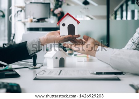 Real estate agents holding model house and give for customers with sale contract,real estate concept.
