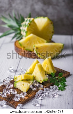 Pineapple cocktail or juice with ice and pineapples on a dark background, Wooden board with fresh sliced pineapple on table