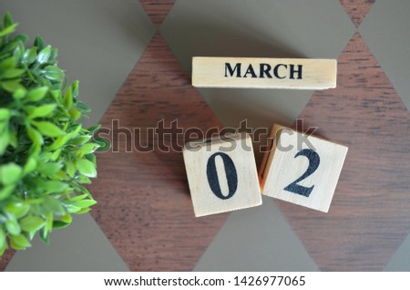 Date of March with leaf on diamond pattern table for background.