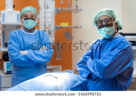 Surgeons team in grown uniform and mask arm cross in operating theater. Surgical team preparing for surgery in operating.