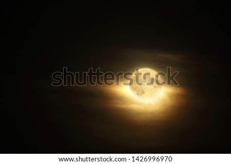 Detailed full moon in dark atmospheric cloudy sky