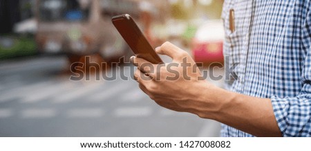 Young man tourist or casual businessman ordering taxi via cab application on smartphone in city street, Male traveler using mobile phone and Searching direction on digital map at Bangkok, Thailand