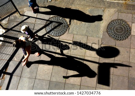 Shadow of pedestrians. Mother and son walking on sidewalk in Porto Alegre, Rio Grande do Sul, Brazil