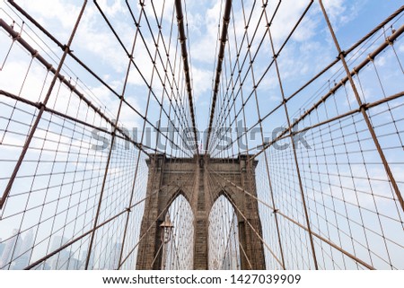Brooklyn Bridge upper part detail against blue cloudy sky background. New York city, Manhattan landmark