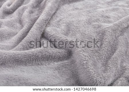 The material texture of the grey blanket.