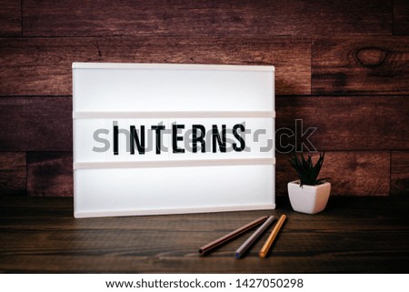 Interns. Text in lightbox. Wooden office table