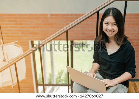 Closeup Asian beautiful woman Wearing a black shirt Sitting in the stairs in the house Use a laptop computer to work happily