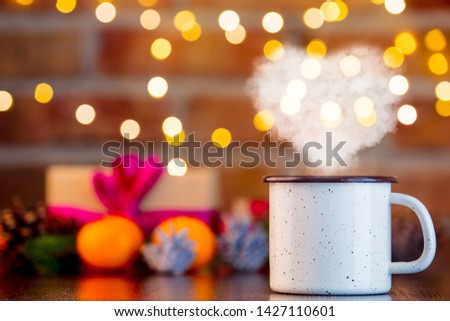 cup of hot drink with heart shape steam on background with fairy lights in bokeh. Christmas Holiday season