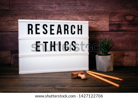 Research Ethics. Text in lightbox. Wooden office table