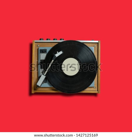 vintage turntable vinyl record player on red background. retro sound technology to play music
