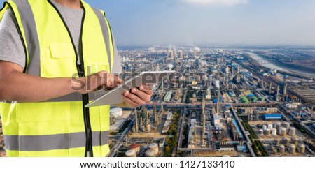 worker working on pad with oil and gas refinery background,Smart