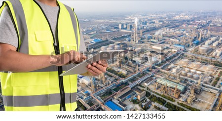 worker working on pad with oil and gas refinery background,Smart