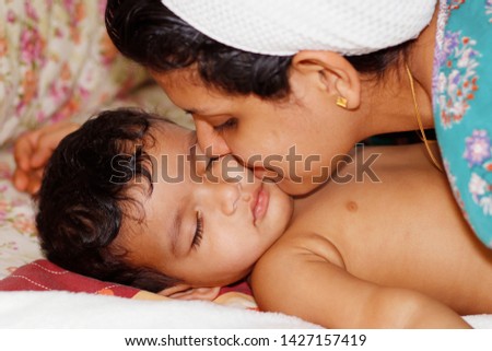 mother kissing her baby boy while on sleeping