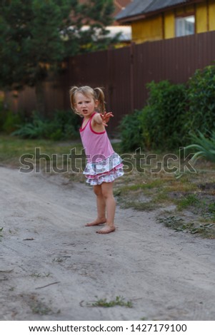 A girl playing with a stick outside in the country. Concept of a happy childhood out of town