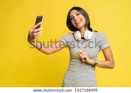Portrait of a pretty girl taking a selfie isolated over color background