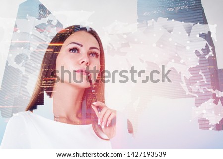 Thoughtful young businesswoman standing over skyscraper background with double exposure of world map. Concept of global trade and transportation. Toned image