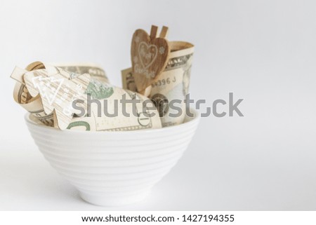 American dollars with decorative clothes pins in the ceramic bowl, light background