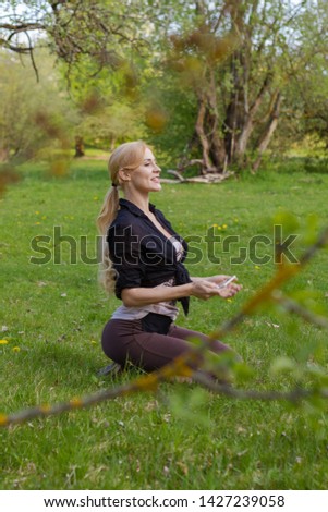 A girl sits on the grass and takes pictures on a smartphone in a green flowered garden