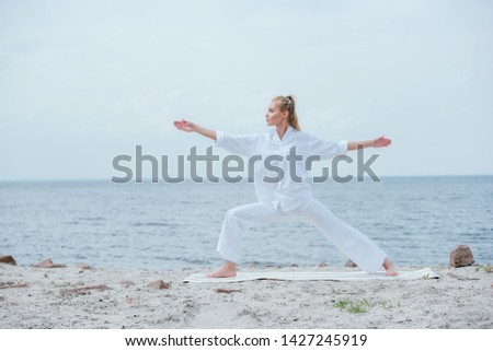 side view of attractive girl practicing yoga and standing with outstretched hands