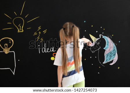 Cute little girl drawing on dark wall